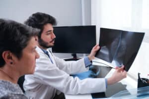 Médico examinando paciente para prevenir cancer de mama e observando a mamografia